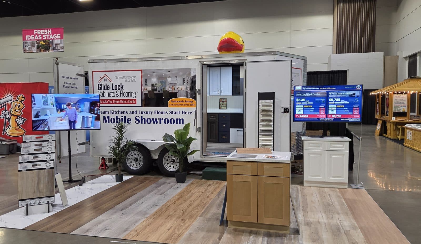 The Glide-Lock Mobile Showroom set up at a home show with cabinets, flooring samples and a monitor on each side